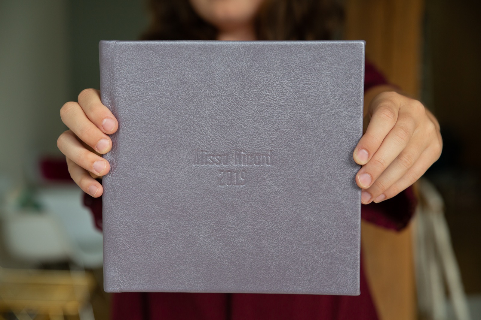 Hands holding a custom debossed gray leather signature album