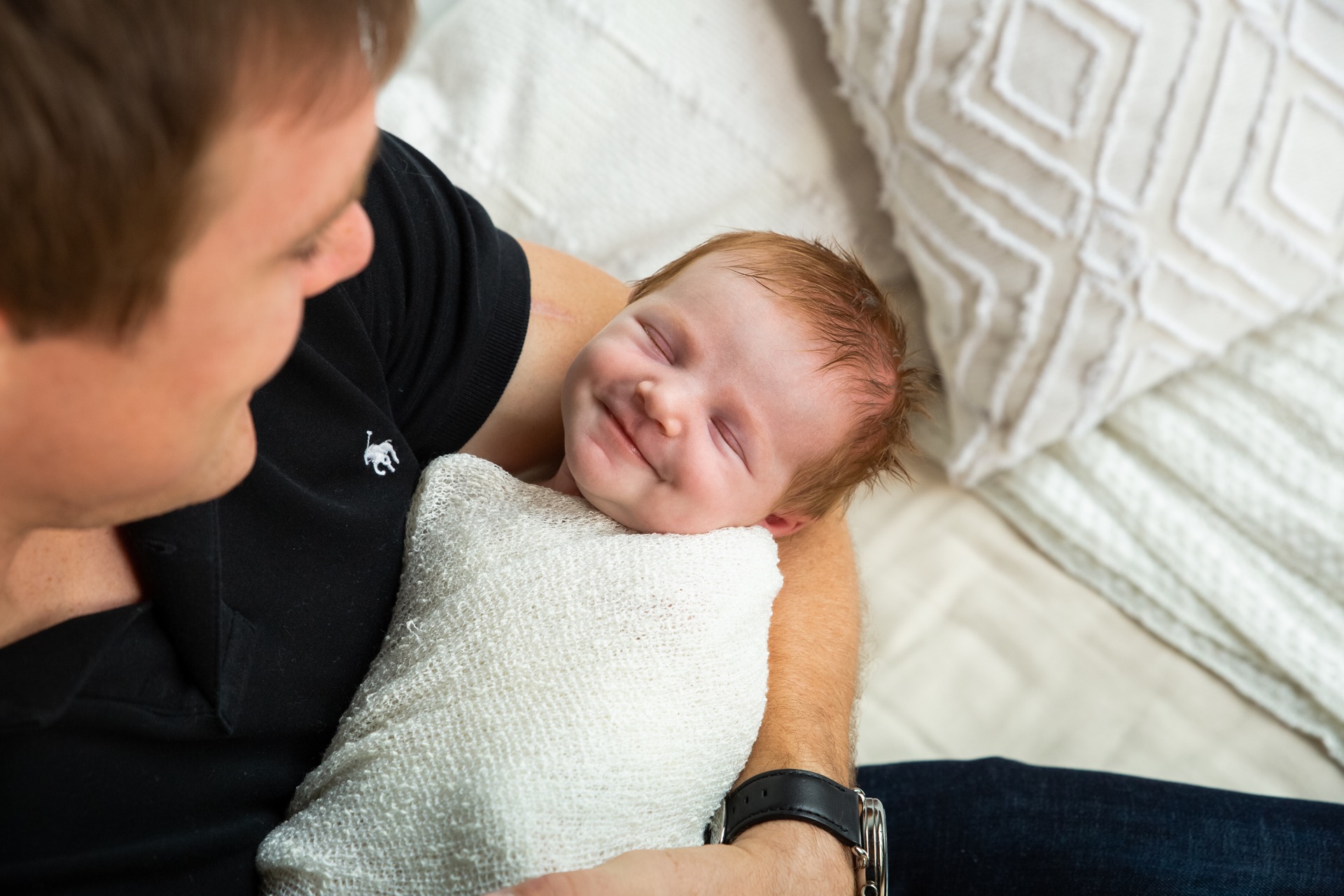 Smiling newborn with dad in-home session Michigan