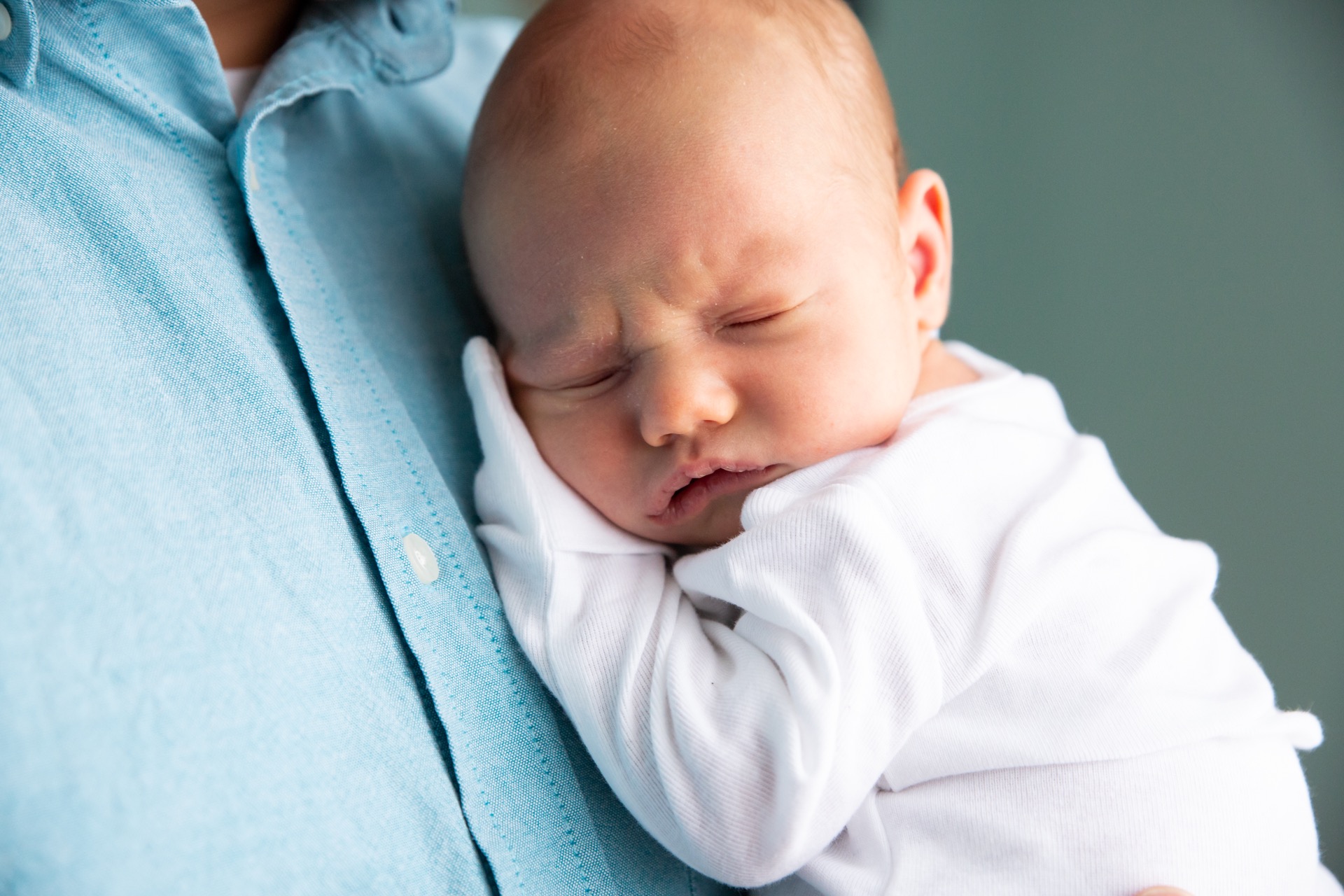 Newborn sleeping on dad newborn session Michigan