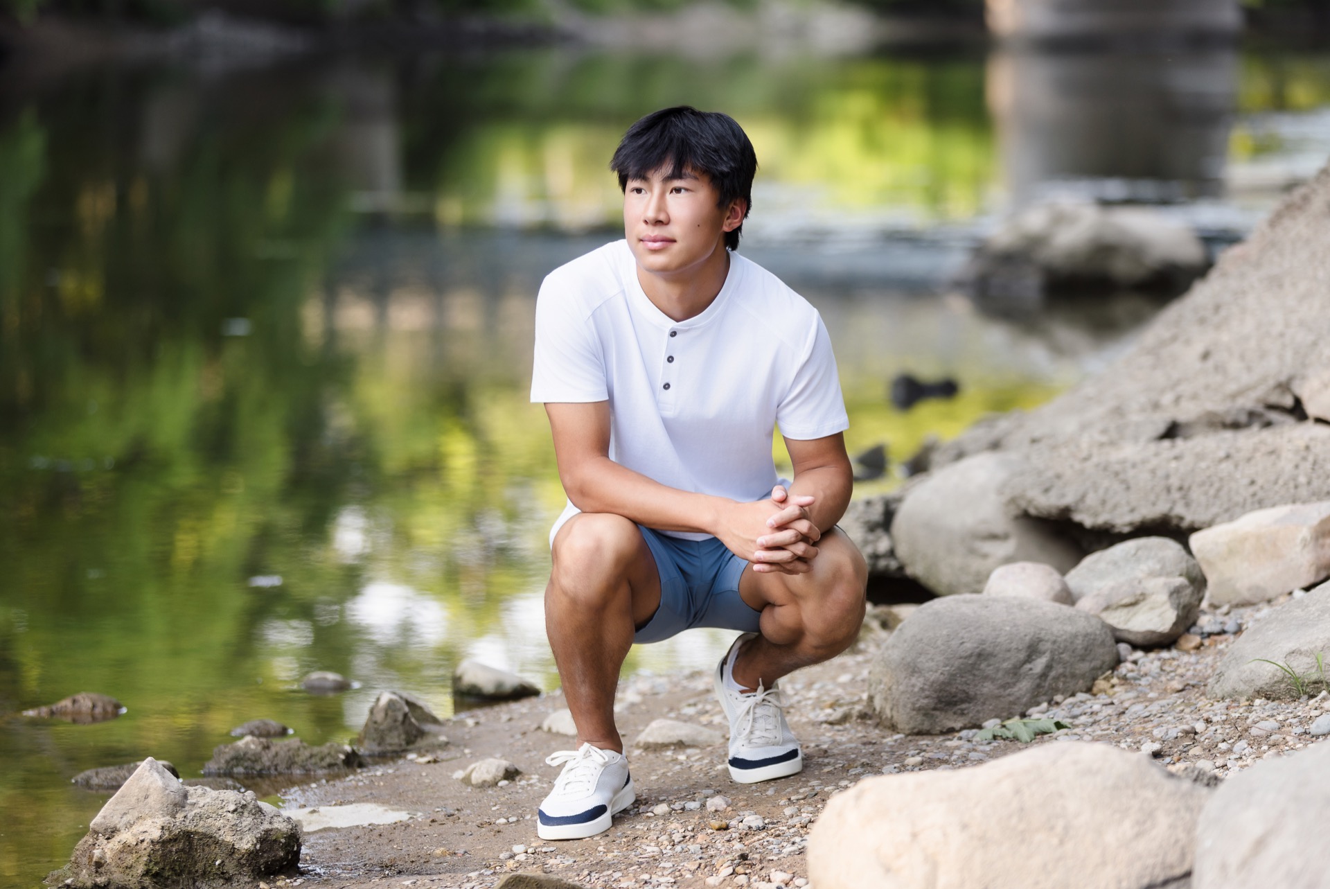 Senior boy portrait on rocks by river Grand Rapids Michigan