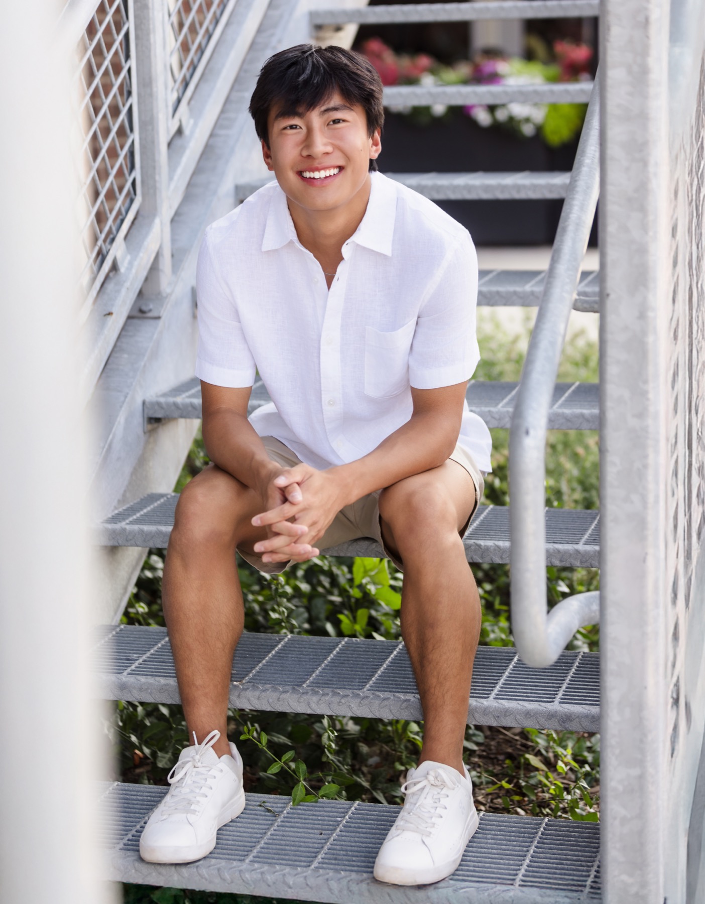 Senior boy sitting on iron stairs during portrait session in the Forest Hills Michigan area