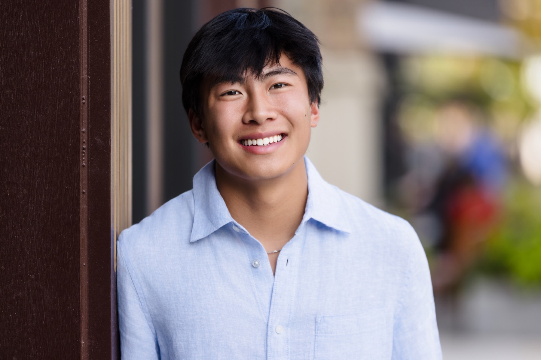 High school senior leaning against wooden doorway near Forest Hills Michigan