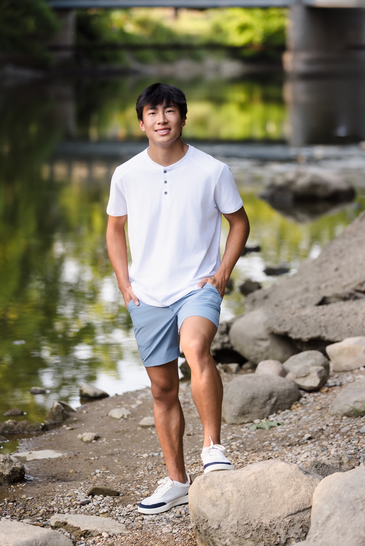 Senior boy standing on rocks along the Thornapple River near Forest Hills Michigan
