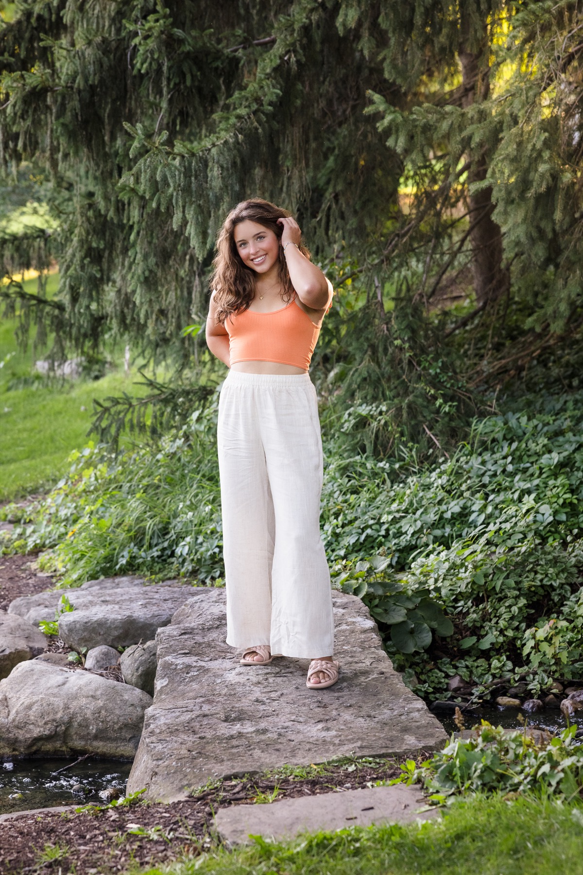 High school senior girl standing on stone steps in a lush garden setting in East Grand Rapids Michigan