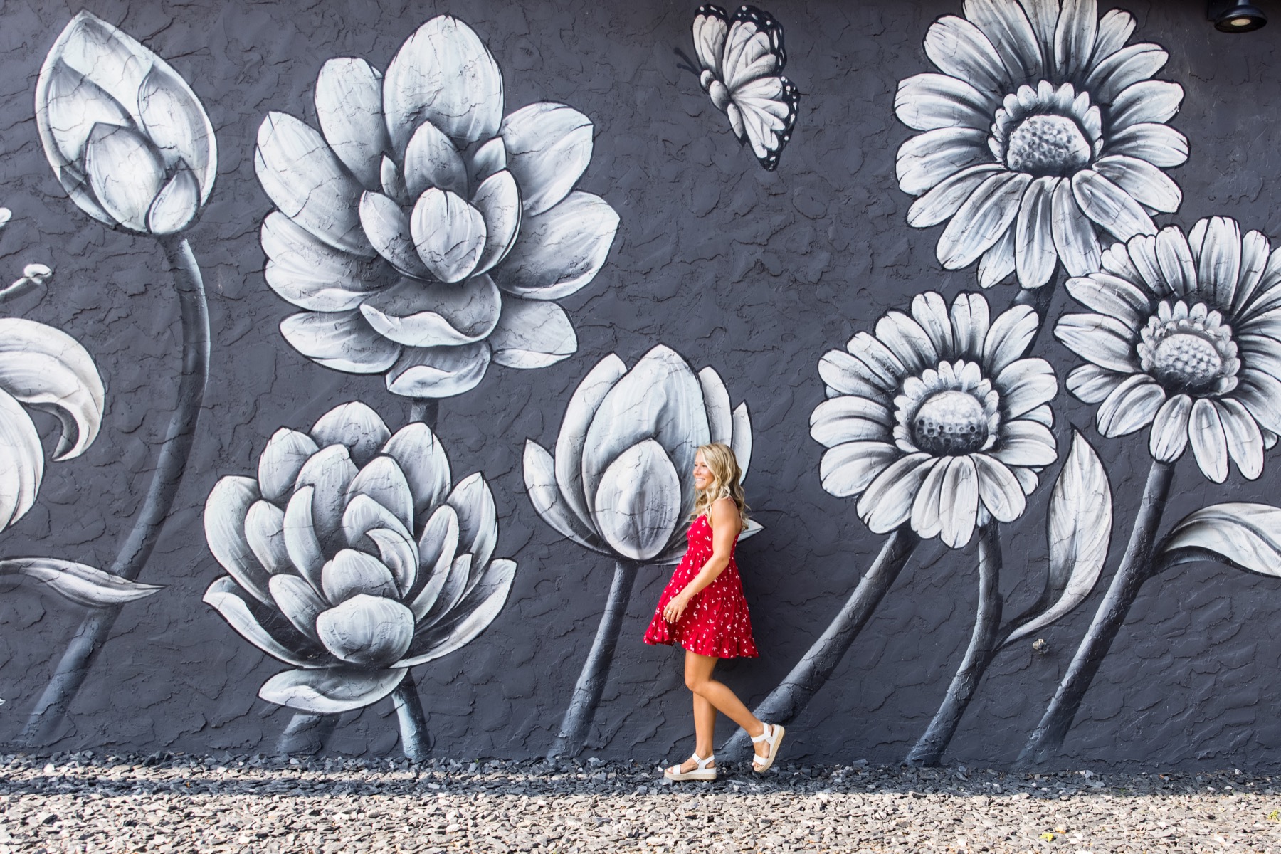 High school senior girl walking in front of large black and white floral mural in downtown Holland Michigan