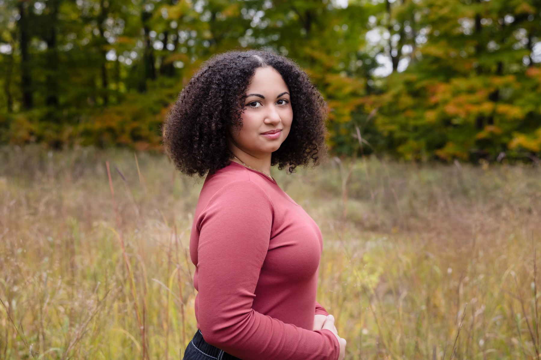 High school senior girl in tall grasses and fall foliage at Grand Ravines Park Jenison Michigan