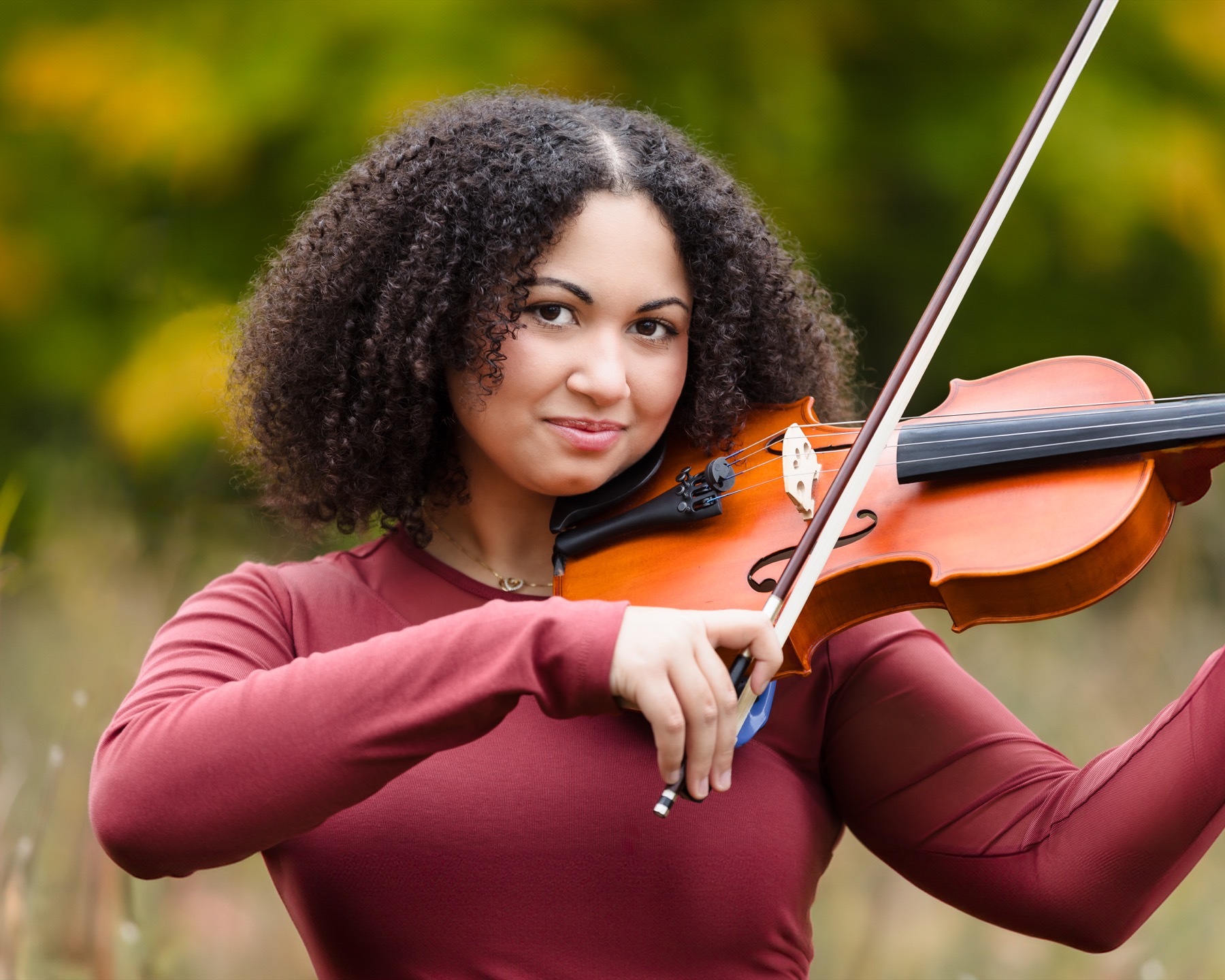 Senior girl holding violin in autumn field during portrait session at Grand Ravines Park Jenison Michigan