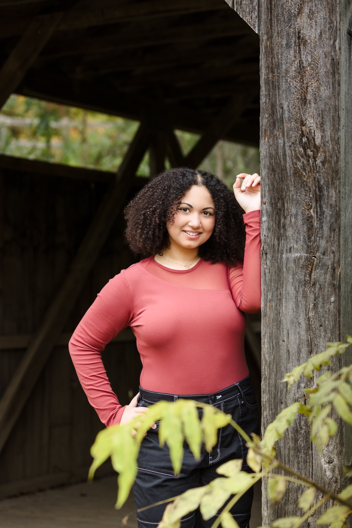 Senior girl leaning in covered bridge doorway at Grand Ravines Park in Jenison Michigan