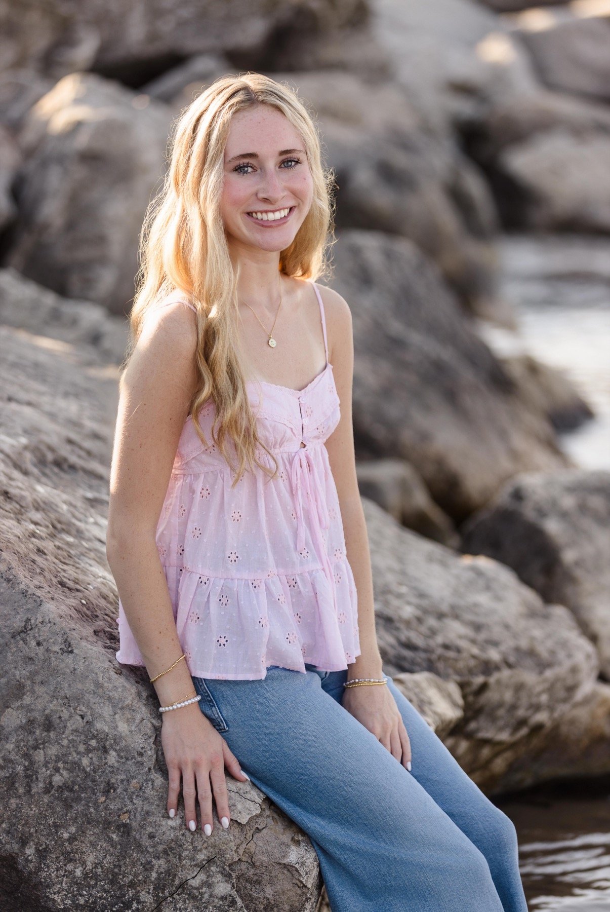 Senior girl sitting on rocks at the edge of Lake Michigan West Michigan