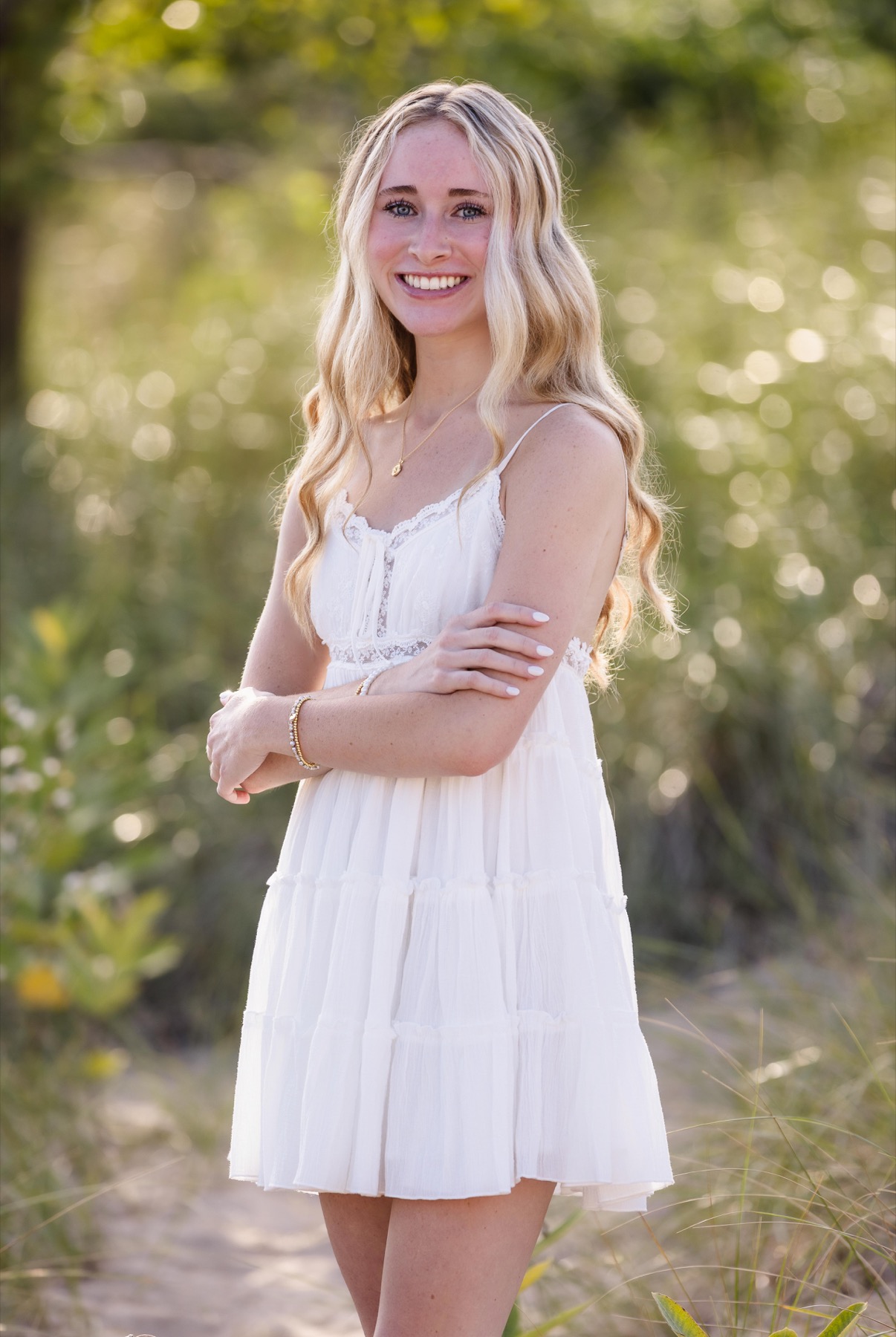 Senior girl in white dress on sandy beach path surrounded by dune grasses on Lake Michigan