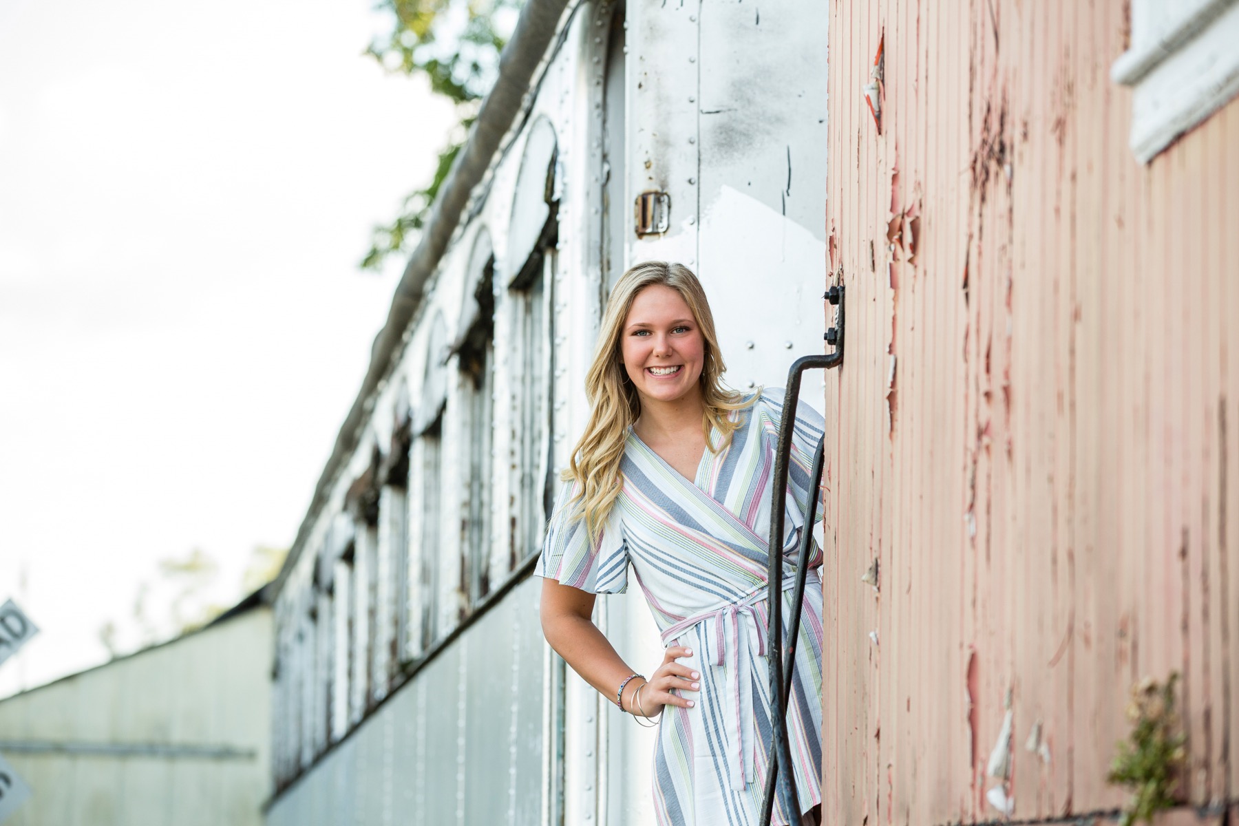 High school senior girl leaning against vintage train car in downtown Rockford Michigan